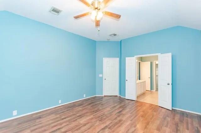 a view of an empty room with window and wooden floor