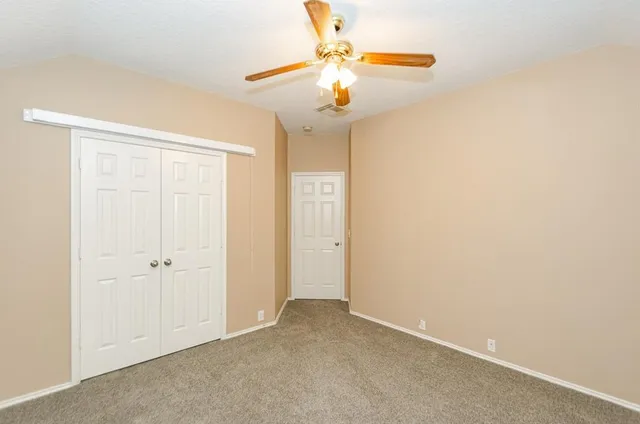an empty room with a chandelier fan and wooden floor