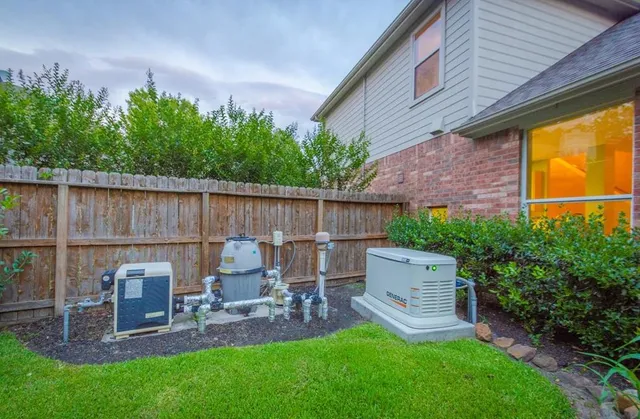 a backyard of a house with table and chairs a barbeque and wooden fence