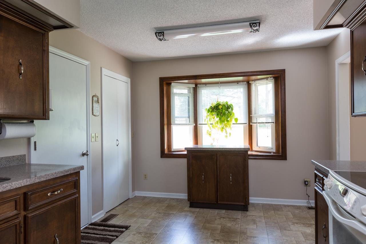 A casual eat-in area sits to one end of the kitchen featuring a charming bay window that allows natural light to flow into the space. The door to the left of the photo leads directly to the garage, making it easy to unload groceries!