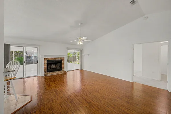 an empty room with wooden floor fireplace and windows