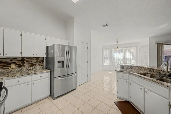 a kitchen with stainless steel appliances granite countertop a refrigerator and white cabinets