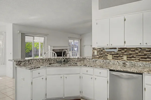 a kitchen with granite countertop a sink and white cabinets