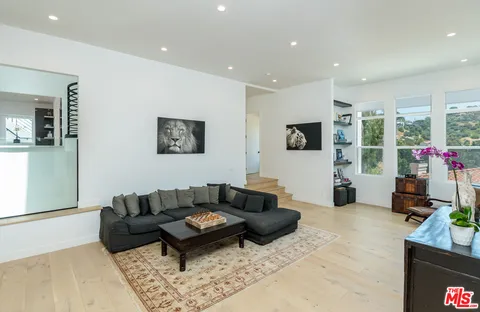 a living room with furniture a flat screen tv and a floor to ceiling window