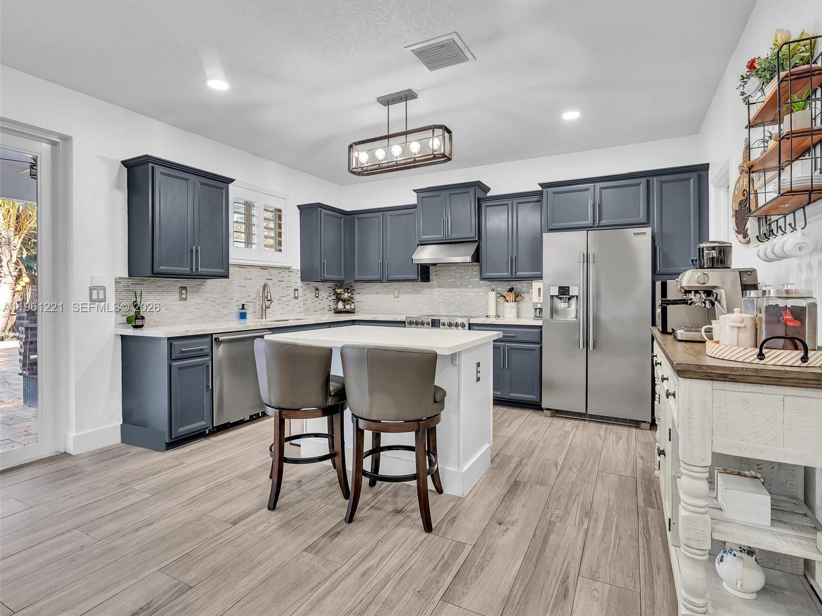 22690 Southwest 127th Court Miami, FL 33170 - Photo 16 of 52 a kitchen with stainless steel appliances a sink a stove a refrigerator cabinets and wooden floor