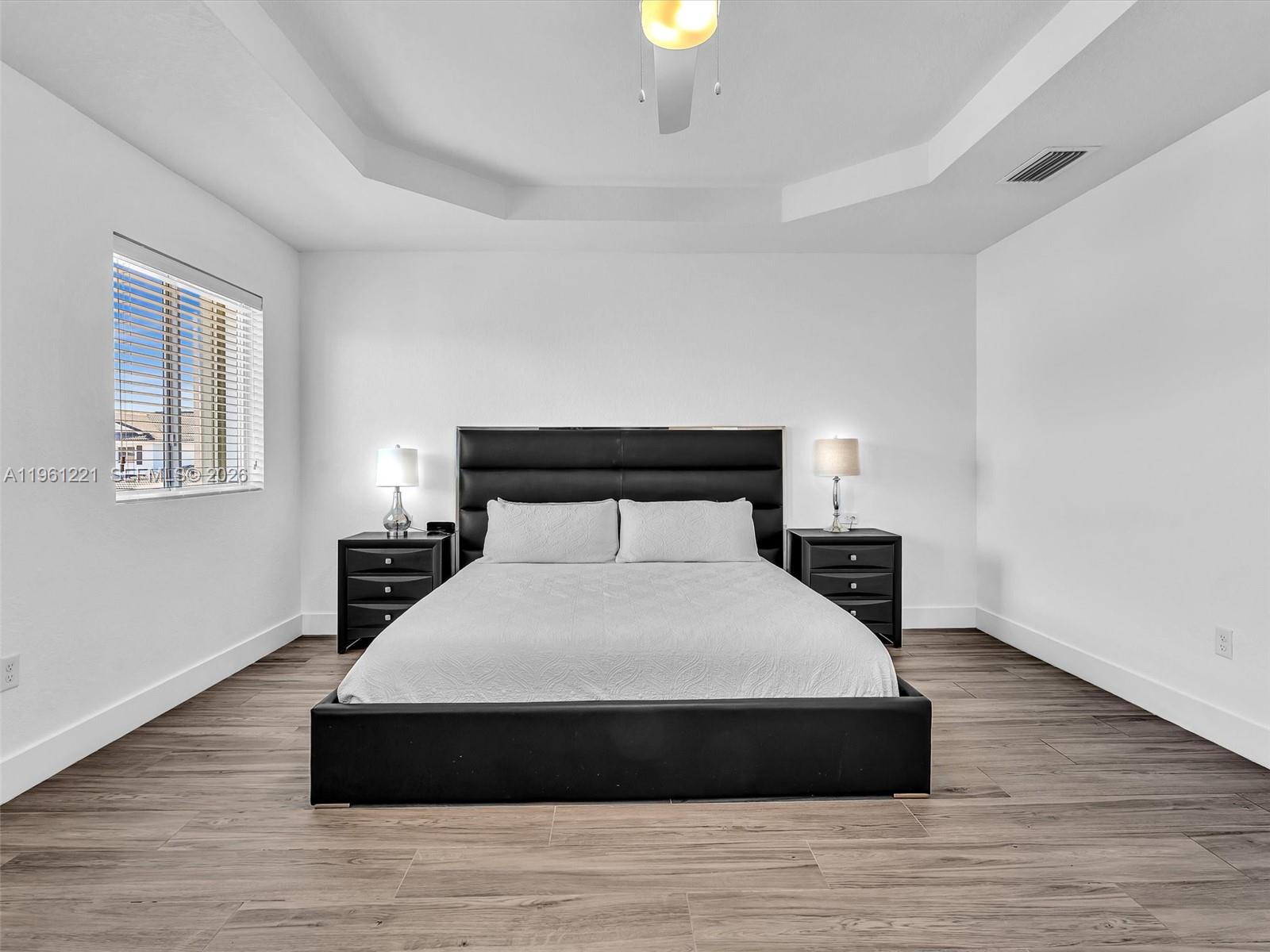 22690 Southwest 127th Court Miami, FL 33170 - Photo 21 of 52 a large bed sitting in a bedroom next to a window with wooden floor