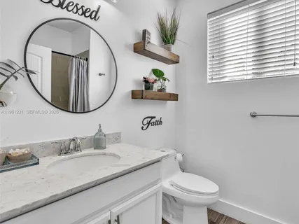 a bathroom with a granite countertop toilet a sink and a mirror