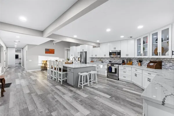 a large white kitchen with lots of counter top space a sink and stainless steel appliances