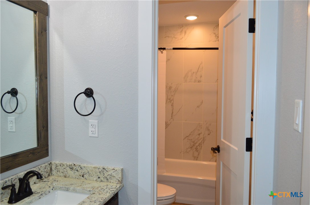1026 County Road 3152 Kempner, TX 76539 - Photo 29 of 48 Hall Full Bath with Granite Countertop, Framed Mirror, and Door Between the Sink Area and the Tub/Shower