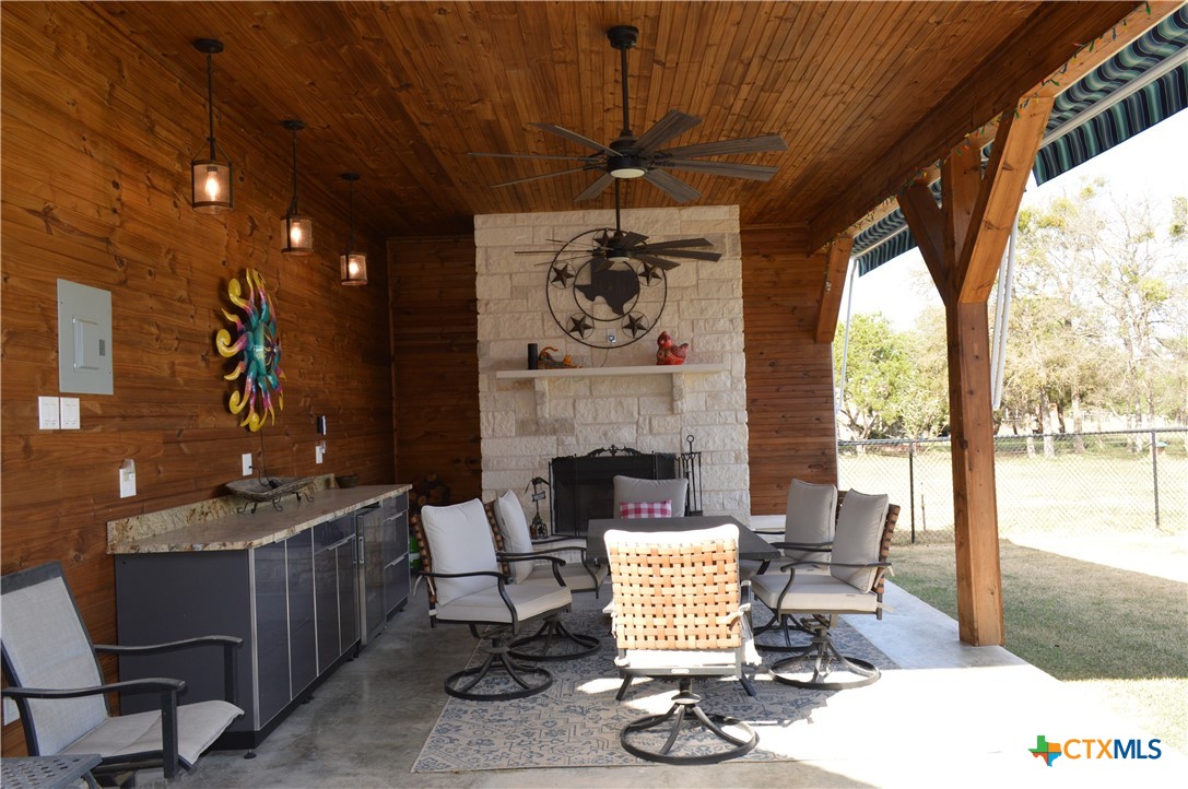 1026 County Road 3152 Kempner, TX 76539 - Photo 36 of 48 Custom, One-of-a-Kind Outdoor Entertainment Area with Cabinets with Granite Countertop, Pendant Lighting, Ceiling Fan, Electric Awning, and Over-Sized Stone Fireplace with Raised Hearth