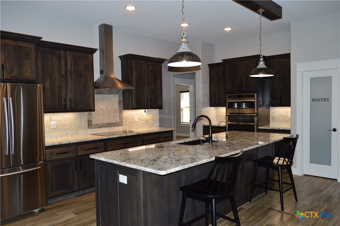 1026 County Road 3152 Kempner, TX 76539 - Photo 8 of 48 a kitchen with granite countertop kitchen island stainless steel appliances a sink and a refrigerator