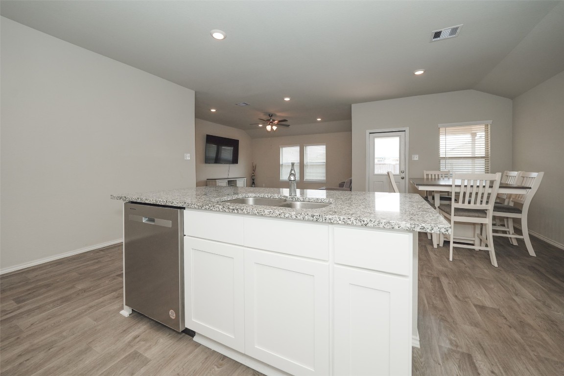 2407 Divot Lane Navasota, TX 77868 - Photo 11 of 37 a kitchen with kitchen island granite countertop wooden floors and white cabinets
