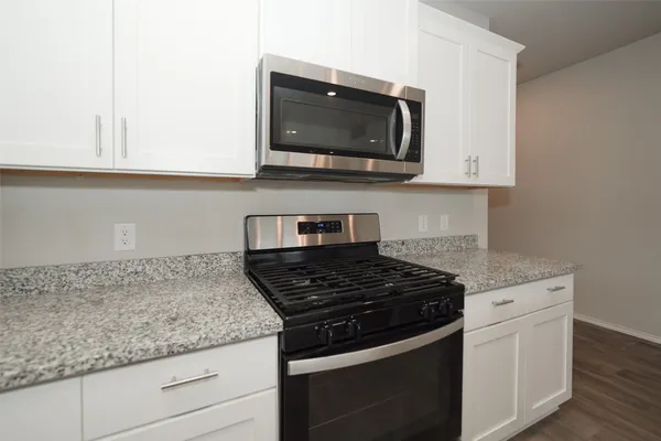 a kitchen with stainless steel appliances granite countertop white cabinets and a stove top oven