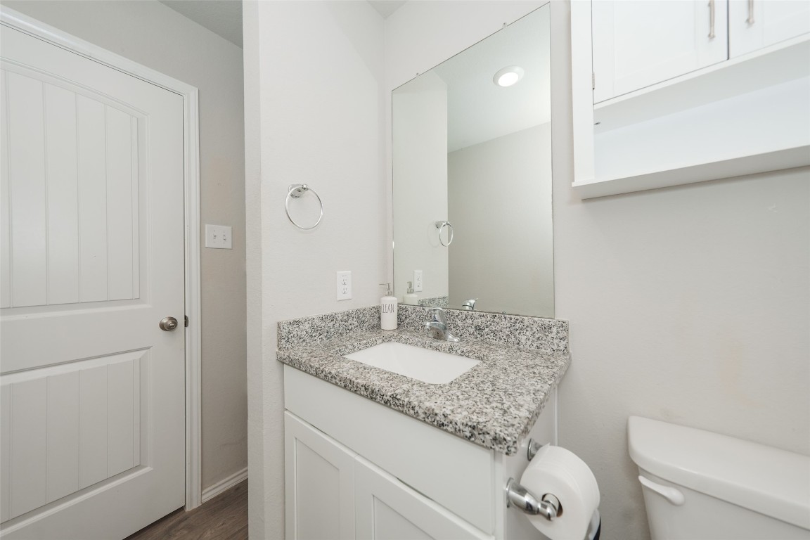 2407 Divot Lane Navasota, TX 77868 - Photo 4 of 37 a bathroom with a granite countertop sink a toilet and a mirror