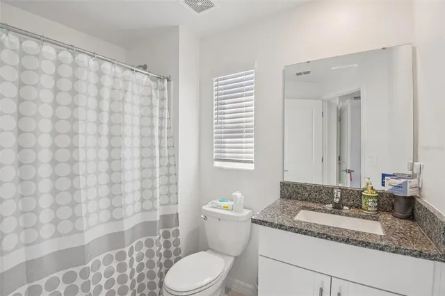a bathroom with a granite countertop sink a toilet and a mirror