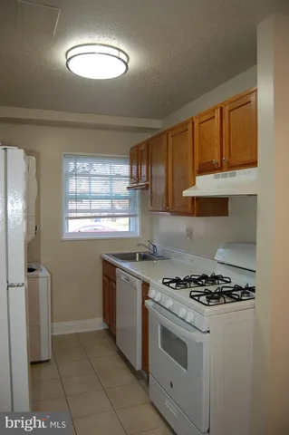 a kitchen with granite countertop a stove a sink dishwasher and a refrigerator