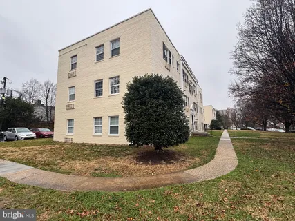 a view of a white house next to a yard with big trees