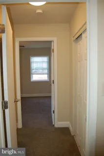a view of an empty room with closet and a window