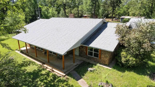 a view of house with yard and trees in the background