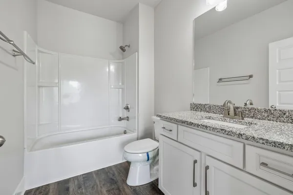 a bathroom with a granite countertop toilet a sink and a bathtub