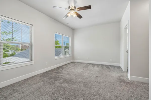 an empty room with windows and fan