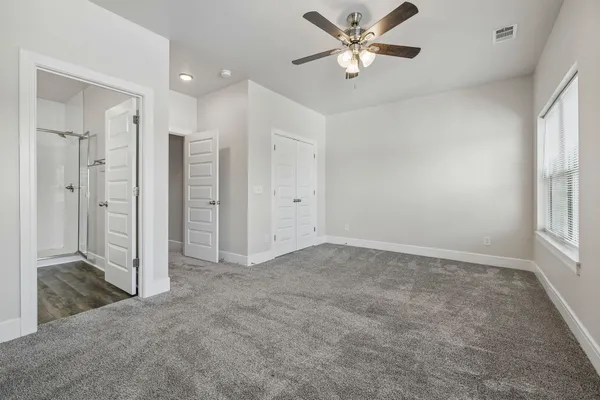 an empty room with chandelier fan and windows