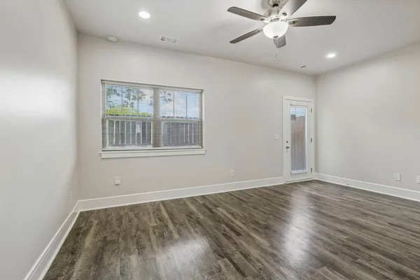 a view of an empty room with wooden floor and a window
