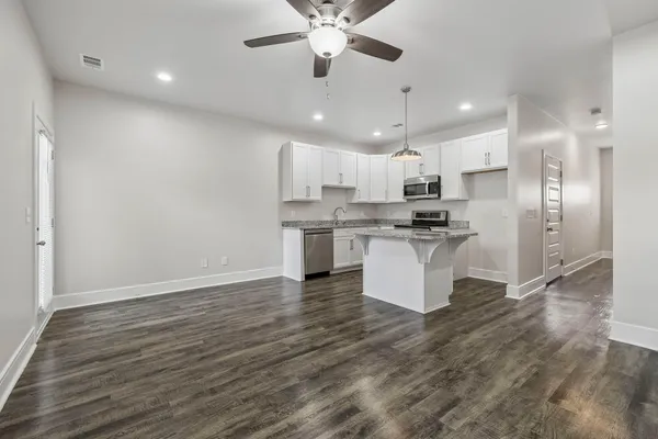 a kitchen with stainless steel appliances kitchen island granite countertop a stove a refrigerator and a sink