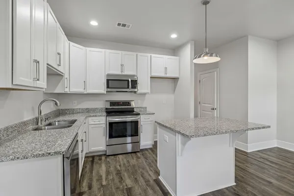 a kitchen with stainless steel appliances granite countertop a sink a stove a refrigerator and island with wooden floor