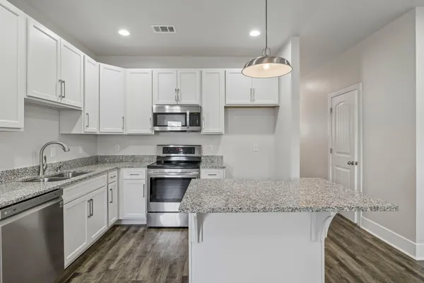a kitchen with stainless steel appliances granite countertop a sink stove and white cabinets