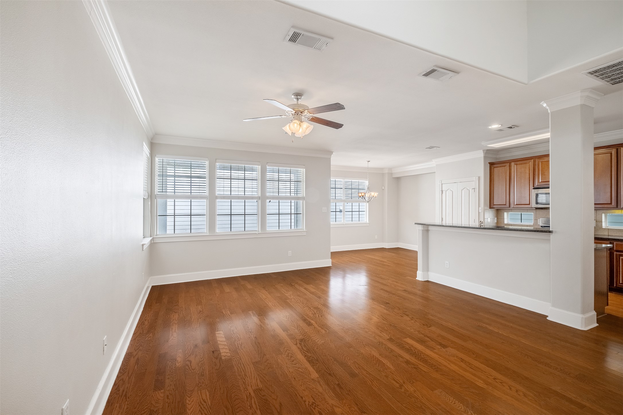 6715 Windrift Way, Unit 8 Austin, TX 78745 - Photo 5 of 24 Rich hardwood flooring grounds this well-lit living space, seamlessly connecting to a functional kitchen with an inviting breakfast bar.