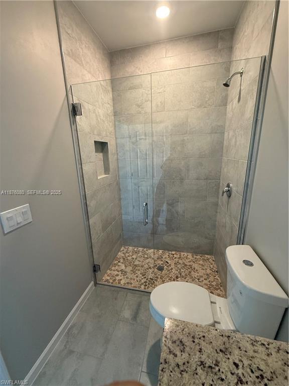 832 Holmes Avenue, Unit 832 Lehigh Acres, FL 33974 - Photo 12 of 24 a bathroom with a granite countertop toilet and a shower