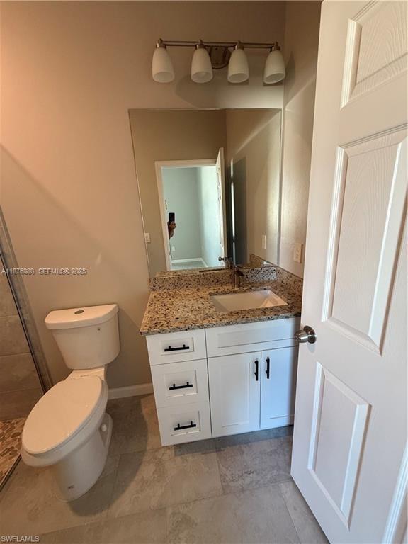 832 Holmes Avenue, Unit 832 Lehigh Acres, FL 33974 - Photo 13 of 24 a bathroom with a granite countertop toilet sink and a mirror