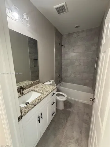 a bathroom with a granite countertop sink a toilet and shower