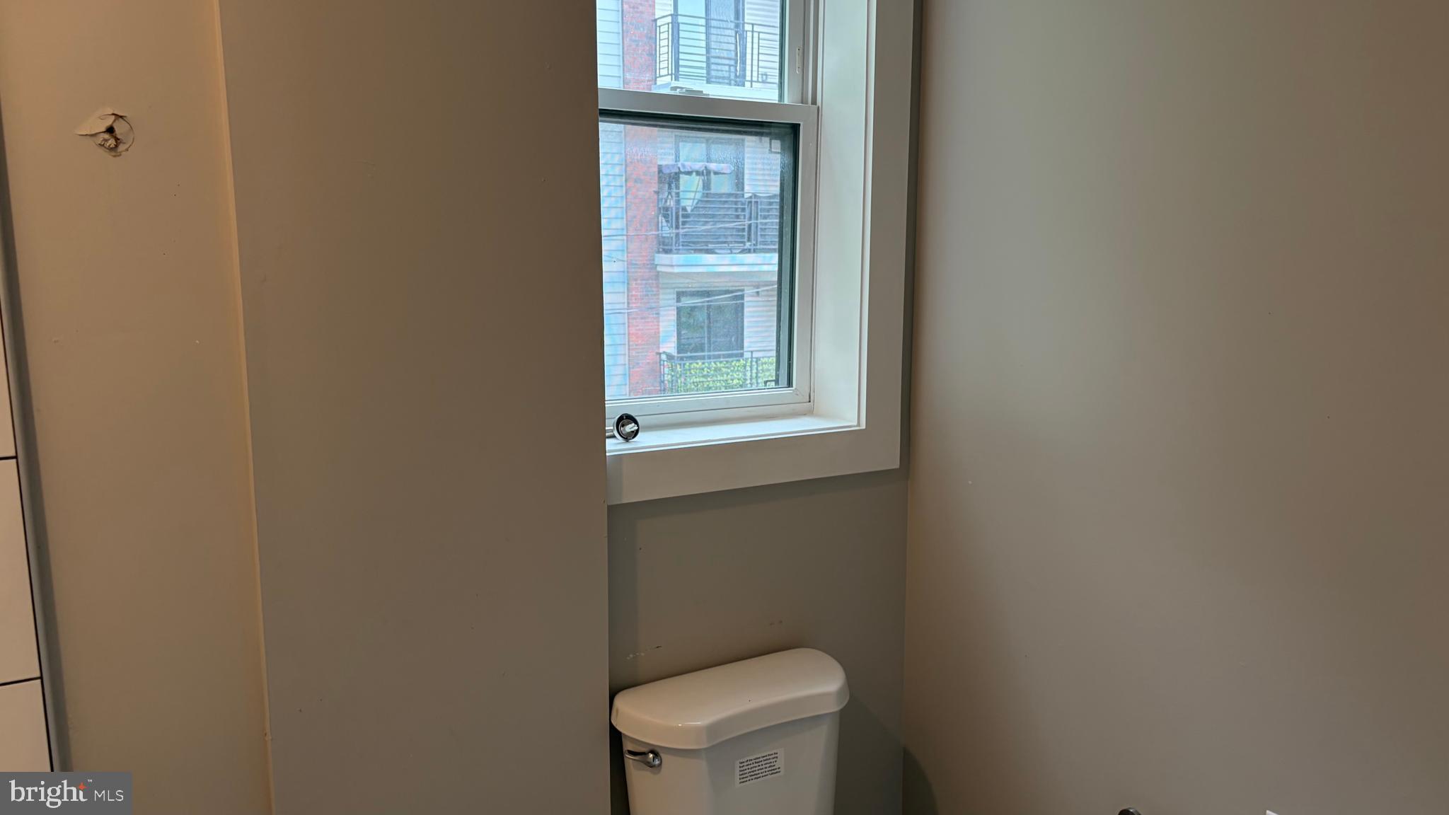 2001 North 33rd Street, Unit 2 Philadelphia, PA 19121 - Photo 25 of 26 a white toilet sitting in a bathroom next to a window