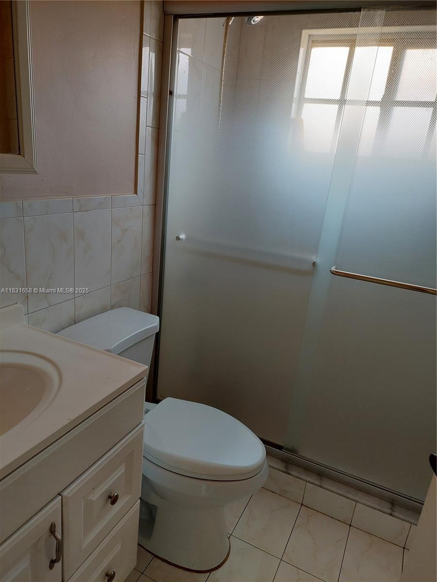 2403 West 76th Street, Unit 203 Hialeah, FL 33016 - Photo 5 of 13 a white toilet sitting next to a bathroom sink and vanity