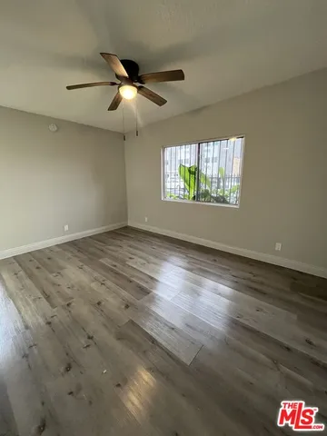 a view of empty room with wooden floor and fan