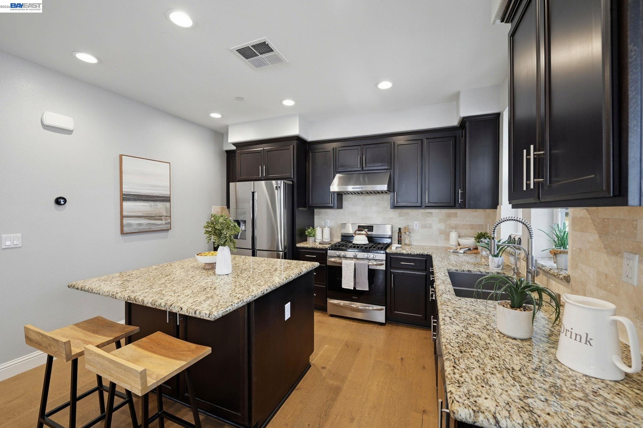 287 Wild Rose Way Milpitas, CA 95035 - Photo 10 of 45 a kitchen with stainless steel appliances granite countertop a stove a sink a microwave a dining table and chairs with wooden floor