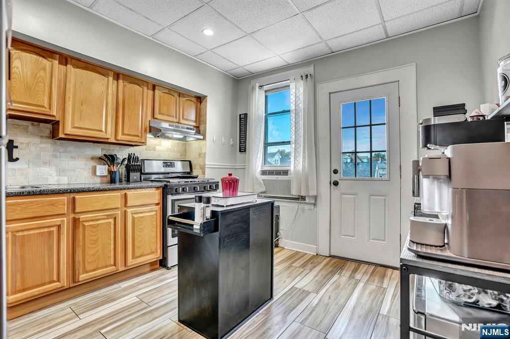 699 Elm Street Kearny, NJ 07032 - Photo 14 of 37 a kitchen with stainless steel appliances granite countertop a refrigerator a sink dishwasher a stove and white countertops with wooden floor