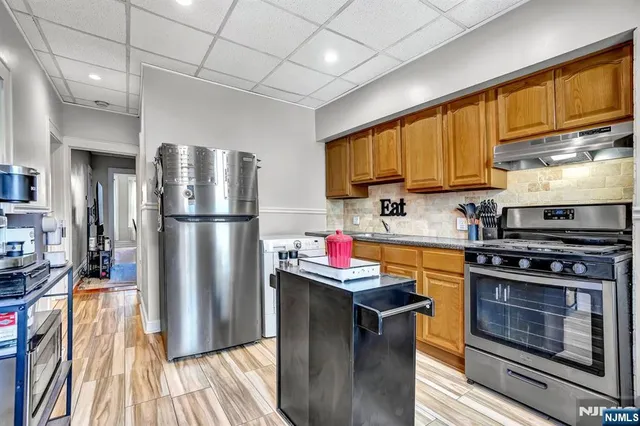 a kitchen with stainless steel appliances granite countertop a refrigerator a stove top oven a sink dishwasher and wooden cabinets