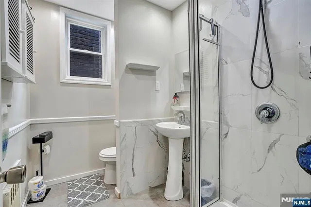 a bathroom with a granite countertop sink a toilet and a shower
