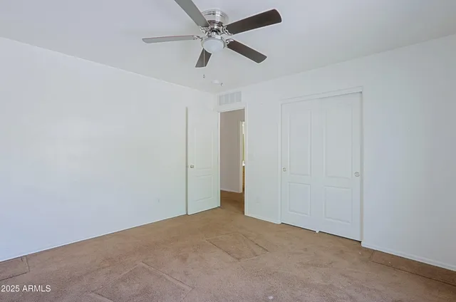 an empty room with chandelier fan