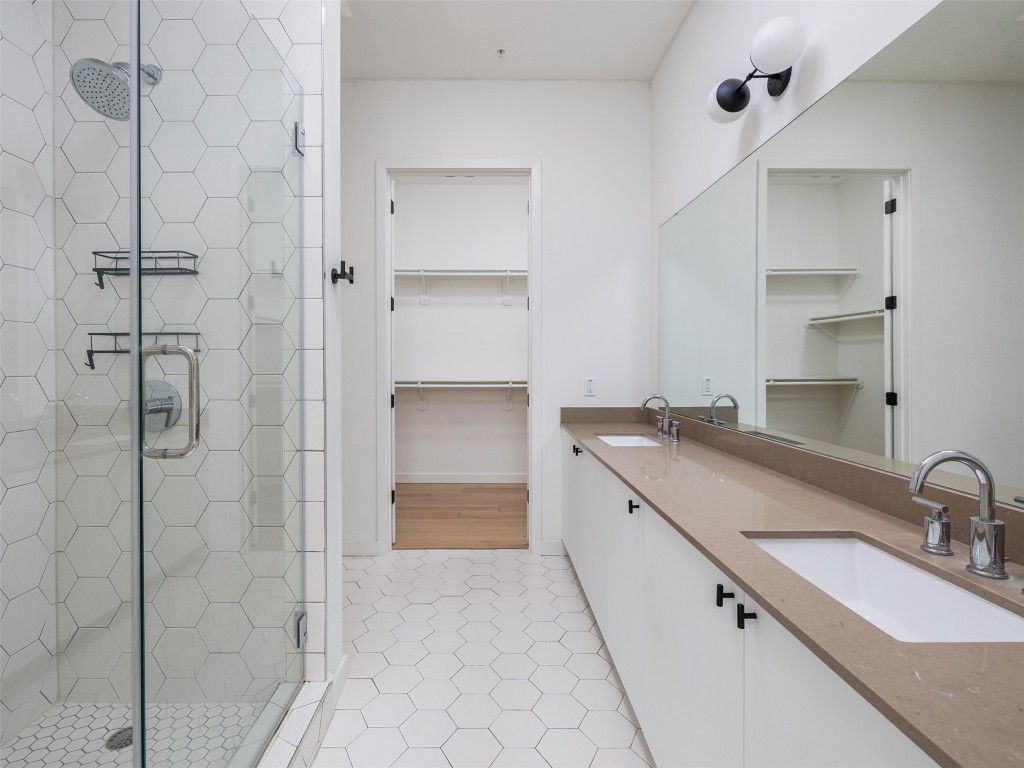 800 Embassy Drive, Unit 237 Austin, TX 78702 - Photo 14 of 35 Full bathroom featuring a walk in closet, a shower stall, double vanity, and light tile patterned flooring