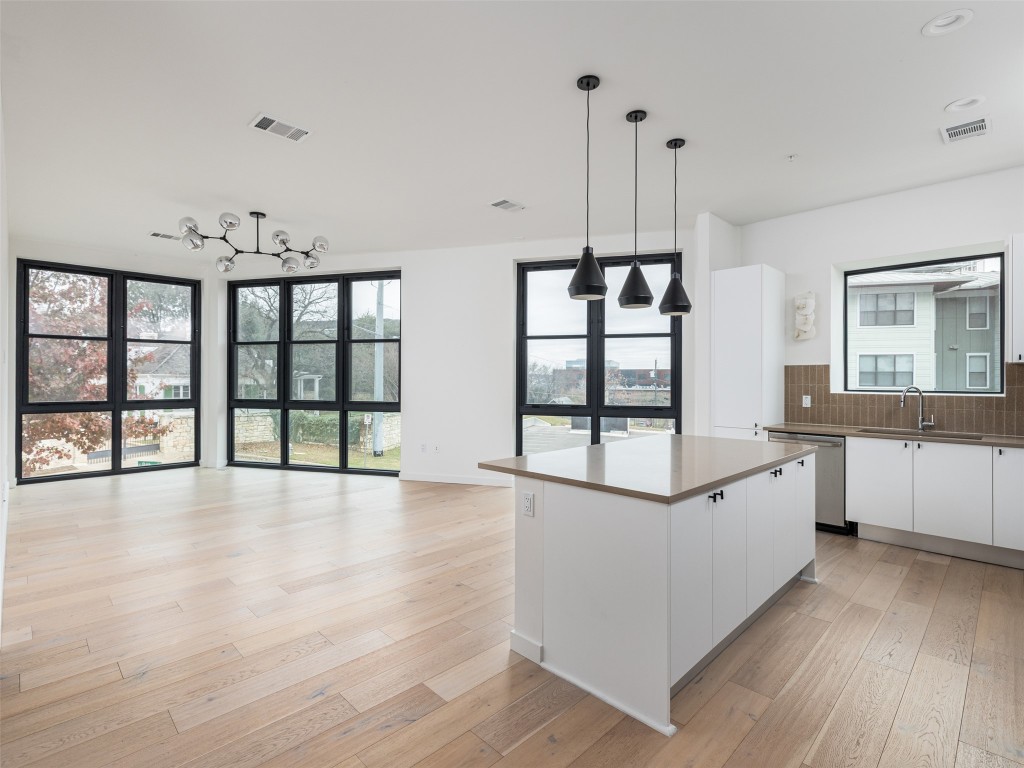 800 Embassy Drive, Unit 237 Austin, TX 78702 - Photo 3 of 35 Kitchen with white cabinets, hanging light fixtures, backsplash, light wood-style floors, and stainless steel dishwasher