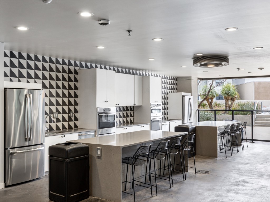 800 Embassy Drive, Unit 237 Austin, TX 78702 - Photo 31 of 35 Kitchen featuring finished concrete floors, a center island, appliances with stainless steel finishes, a breakfast bar, and recessed lighting