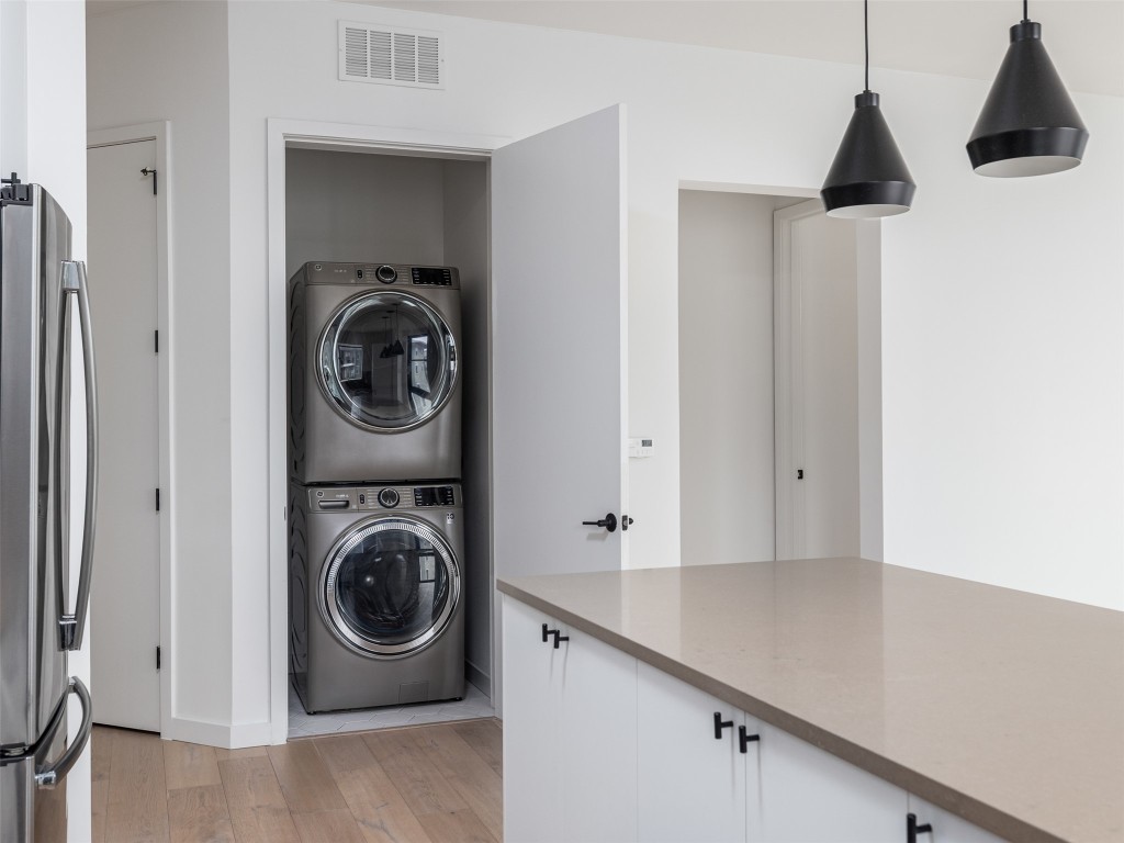 800 Embassy Drive, Unit 237 Austin, TX 78702 - Photo 7 of 35 Laundry area featuring stacked washing machine and dryer and light wood-style flooring