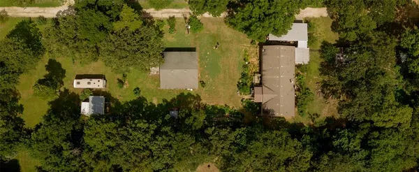 an aerial view of residential house with outdoor space and trees all around