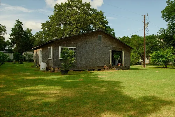 a backyard of a house with plants and large tree