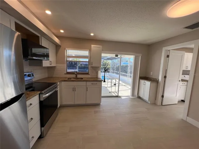 a large kitchen with stainless steel appliances granite countertop a stove a sink and a refrigerator