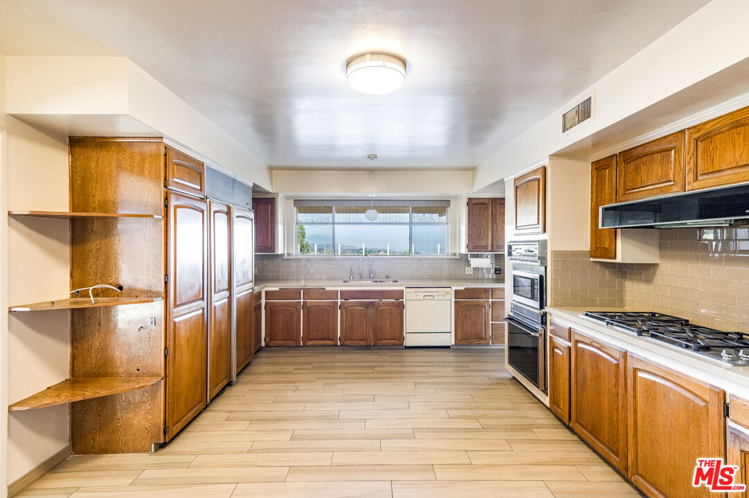 1950 Carla Ridge Beverly Hills, CA 90210 - Photo 12 of 29 a kitchen with stainless steel appliances granite countertop a stove refrigerator and cabinets